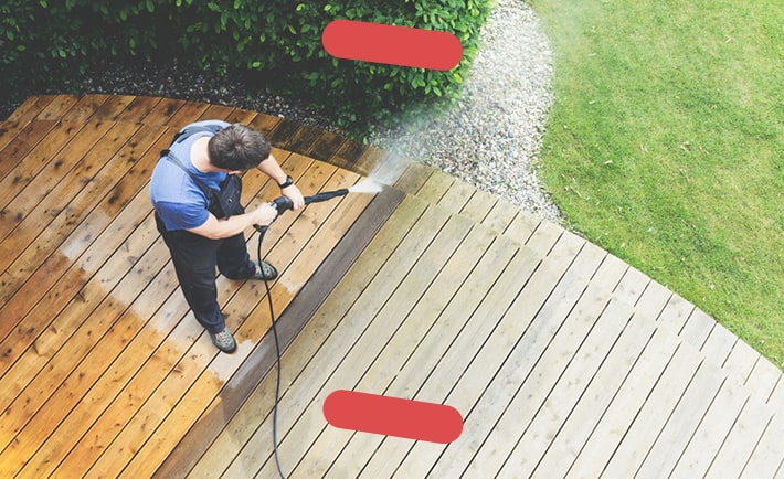 Man pressure washing deck